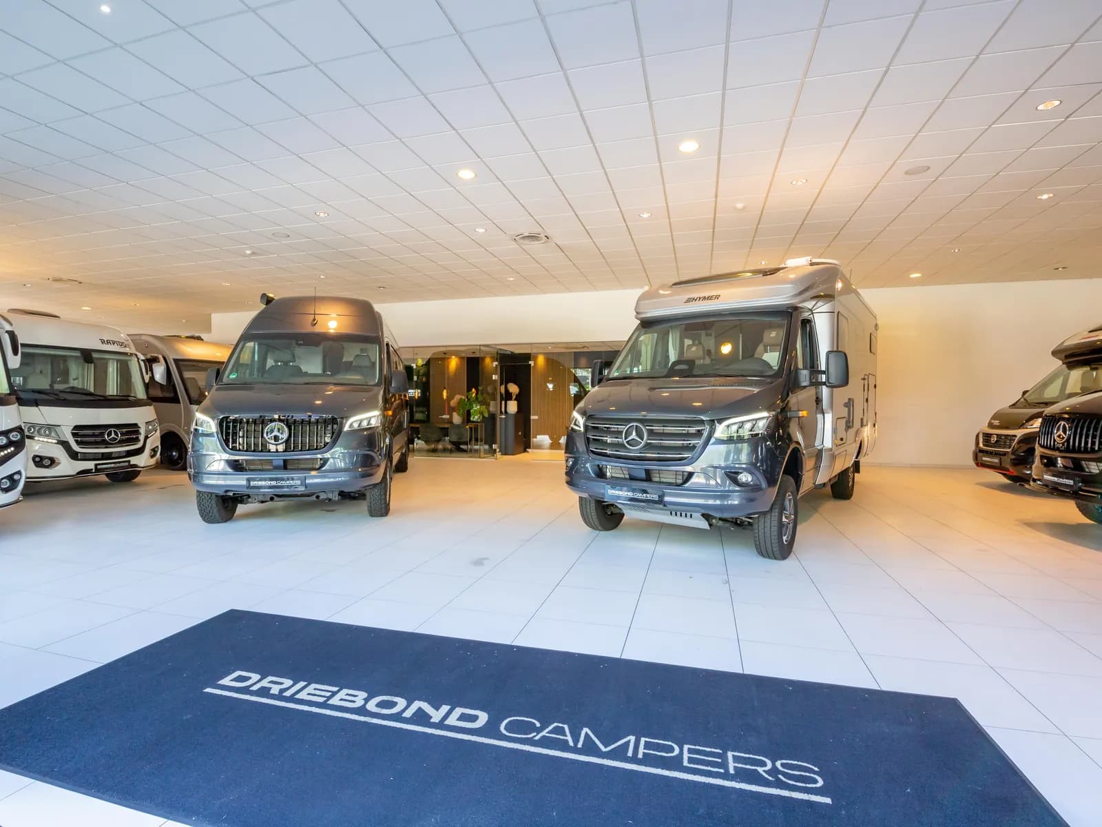 De showroom van Driebond Campers met buscampers op Mercedes-Benz Sprinter en de Driebond-mat bij de ingang