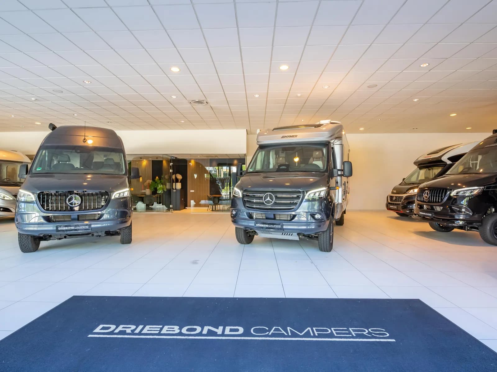 De showroom van Driebond Campers in Groningen, met de Driebond-mat bij de ingang en campers klaar om te bekijken
