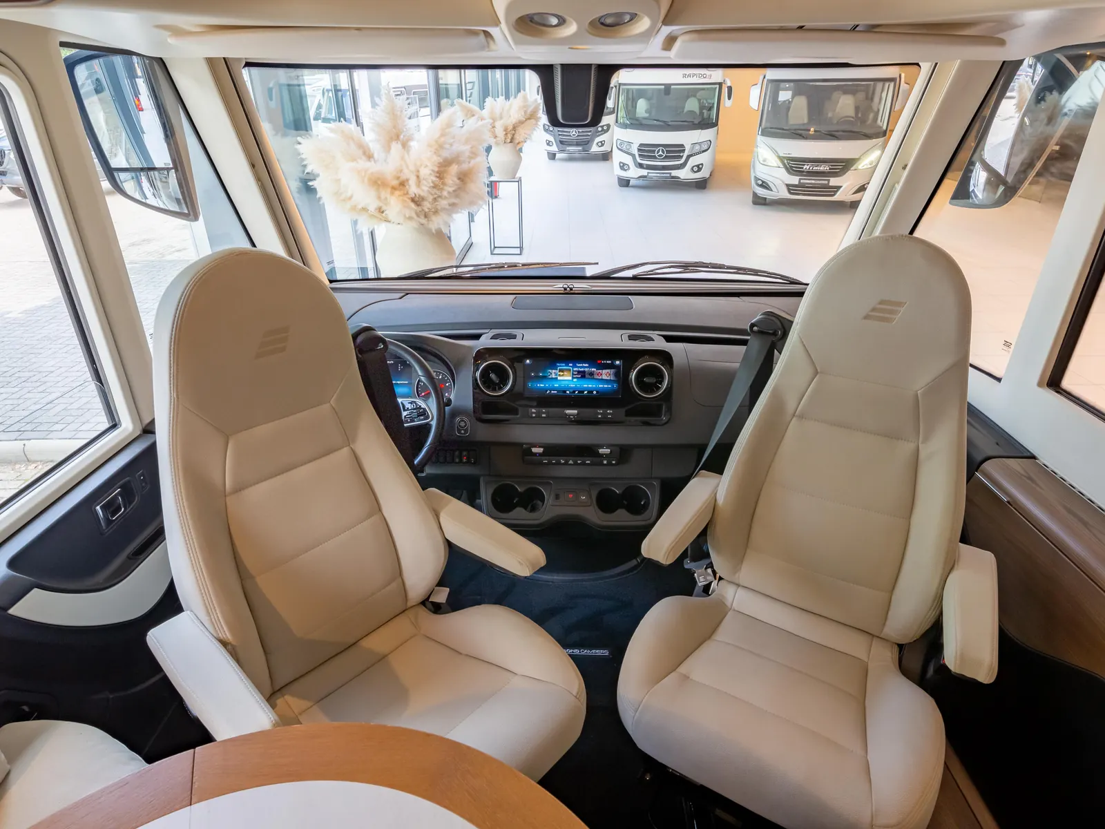 Cabinestoelen en dashboard van een Hymer integraal, met zicht op de showroom