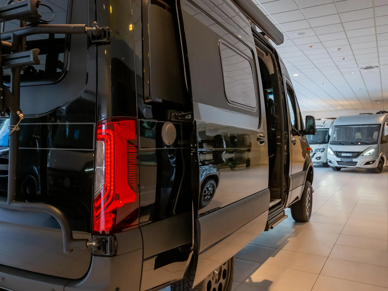 Buscamper met fietsdrager tussen de campers in de showroom van Driebond Campers